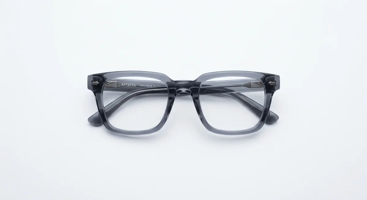 Folded smoky-grey acetate Mykita frames photographed from above on white